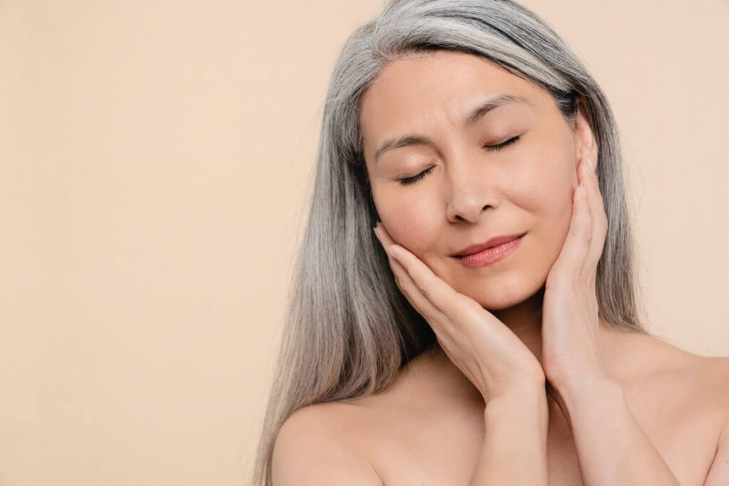 Older woman gently touching her face after receiving anti-wrinkle skin treatment by Dr. Shauna Watts in Central Coast and Newcastle.